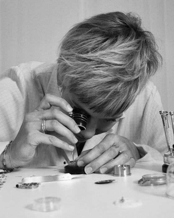 A watchmaker looking through an eyepiece as she works on a watch